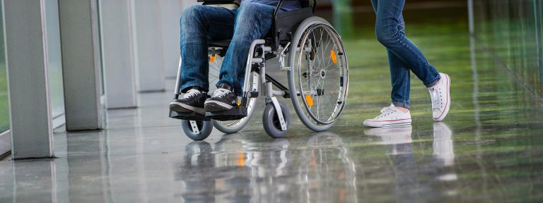 A person in a wheelchair being assisted by another, reflecting the types of personal injury cases that Toronto lawyers, specializing in long-term disability and accident claims, handle. This scenario underscores the advocacy provided by personal injury attorneys, including slip and fall and brain injury lawyers, at a dedicated law firm in Toronto, for individuals facing mobility challenges after accidents